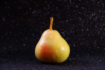 Yellow pear on a shiny black background. Bright juicy fruit.