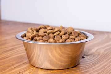 Dog food in bowl on wooden table. White background