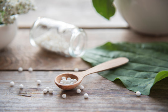 homeopathic granules, medicinal herbs on a natural wooden table on a natural background. alternative medicine and homeopathy