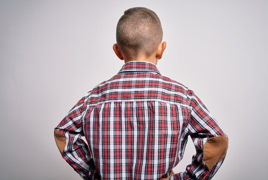 Young little caucasian kid with blue eyes wearing elegant shirt standing over isolated background standing backwards looking away with arms on body