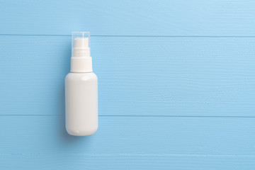 Alcohol spray disinfectant in a white plastic container on a blue wooden background. Disinfection of hands and objects. Copyspace.