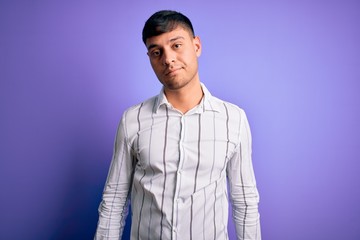 Fototapeta premium Young handsome hispanic man wearing elegant business shirt standing over purple background looking sleepy and tired, exhausted for fatigue and hangover, lazy eyes in the morning.