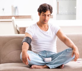 Young man measuring blood pressure at home