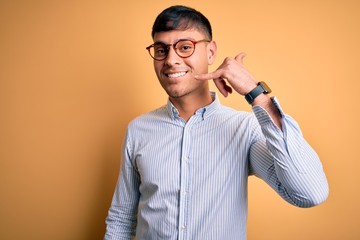 Young handsome hispanic business man wearing nerd glasses over yellow background smiling doing...