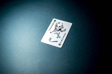 Joker card on black background under light