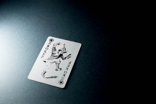 Joker card on black background under light
