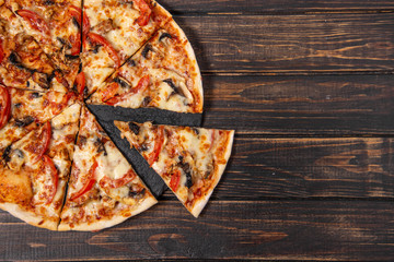 Pizza with mushrooms and chicken on a wooden table.