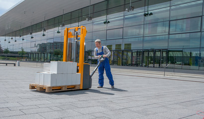 man in overalls operates a forklift loaded with boxes