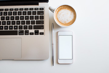Flat lay business feminine workplace with mockup smartphone, mockup laptop, coffee, and green...