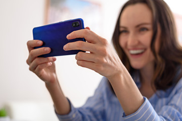 one smiling woman in blue shirt talks on phone, video calls, takes selfies, online game