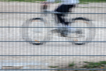 Ein nur teilweise erkennbarer Junge, mit dunkler Hose und blauem Hemd, fährt auf seinem Fahrrad...