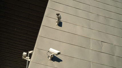 Urban scene. Surveillance cameras on a gray wall. Safety and security. The bright sun falls on the wall. Security technology.