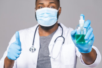 African american doctor man in gown face mask gloves isolated on grey background. Epidemic pandemic...
