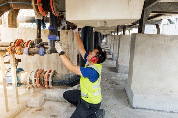 Engineers inspect machine operations. Cooling tower in a large building That has been used for many years For safety