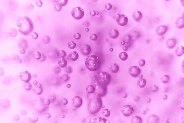 Many round bubbles of the shower gel on the purple background.
