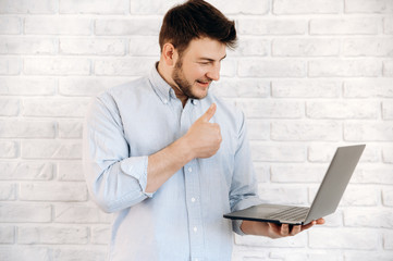 Skype video call using laptop. The guy stands on a white background holding a laptop in his hand...