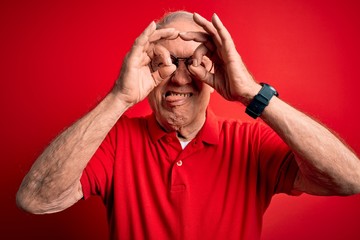 Grey haired senior man wearing glasses and casual t-shirt over red background doing ok gesture like...