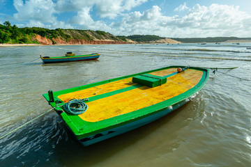 Baia Formosa, near Natal, Rio Grande do Norte, Brazil on June 7, 2014. A popular beach for surfing. Colorful boats with cliffs in the background