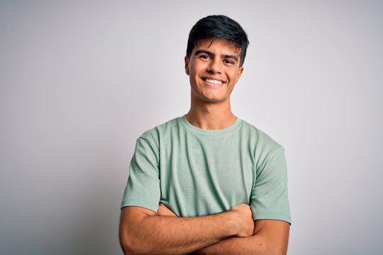 Young handsome man wearing casual t-shirt standing over isolated white background happy face smiling with crossed arms looking at the camera. Positive person.