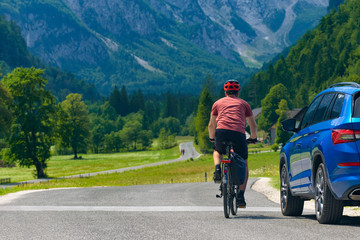Traveling cyclist on road and car in the valley