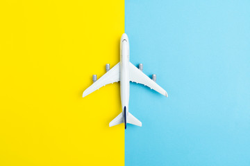 Flat lay miniature airplane model isolated on yellow and blue background