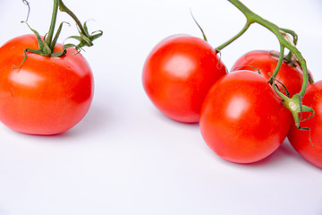 Tomatoes and a green stalk on a white background.