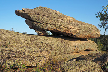 The flat fantastic stone on the big brown rock with spots of lichens, yellow grass, the clean blue sky