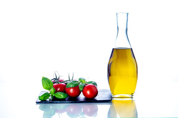 olive oil, tomatoes, basil, garlic, on slate and white background