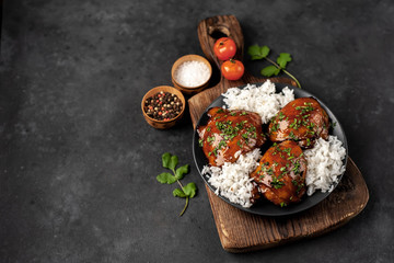 grilled sweet chicken thighs and  cooked rice on a stone background 
with copy space for your text. Asian food