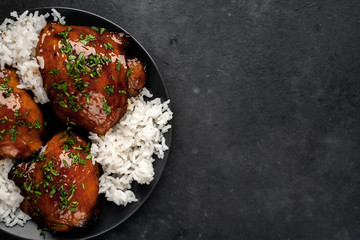 grilled sweet chicken thighs and  cooked rice on a stone background 
with copy space for your text. Asian food