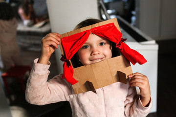 Caucasian girl child plays in a cardboard theater
