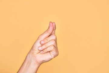 Hand of caucasian young man showing fingers over isolated yellow background holding blank space with thumb finger, business and advertising