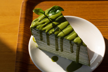 A piece of green tea cake roll, white wipping cream inside for tea time put on wood table