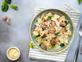 vegan pasta with mushrooms and spinach on a gray stone background. healthy food. top view horizontal image. copy space.