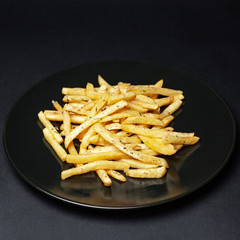french fries on a black plate on a black background