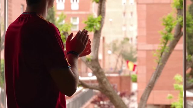 Joven aplaudiendo desde la ventana a los servicios m&eacute;dicos en Espa&ntilde;a en su lucha contra el COVID-19, foco en el hombre