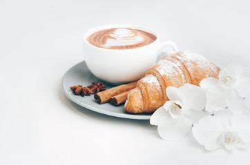 Fresh baked croissant with coffee cup and latte art, cinnamon