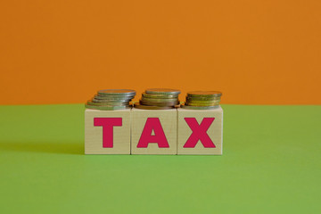Rows of coin stacks with toy blocks symbolizing taxation.