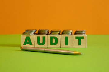 A metal handle and rows of coin stacks with toy wooden blocks symbolizing a financial audit. Space for additional text.