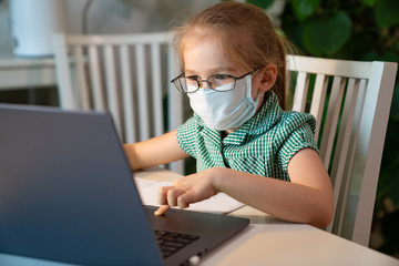 small girl in glasses and mask learn on laptop