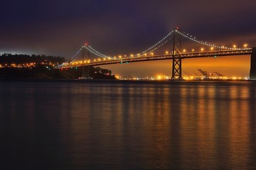 Fototapeta na wymiar Illuminated Bridge Over Water At Night