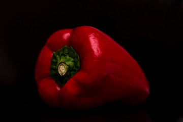 Juicy red bell pepper on a black background. Healthy eating and vegetarianism. Close-up.