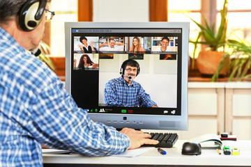 A computer screen in a home office showing a group of people and the tutor having fun with E-learning