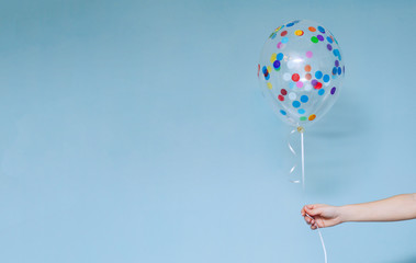 stylish birthday party or holidays with balloons close up. Hand  holding blue colorful balloon indoor on blue background. background for birthday greeting card or other event