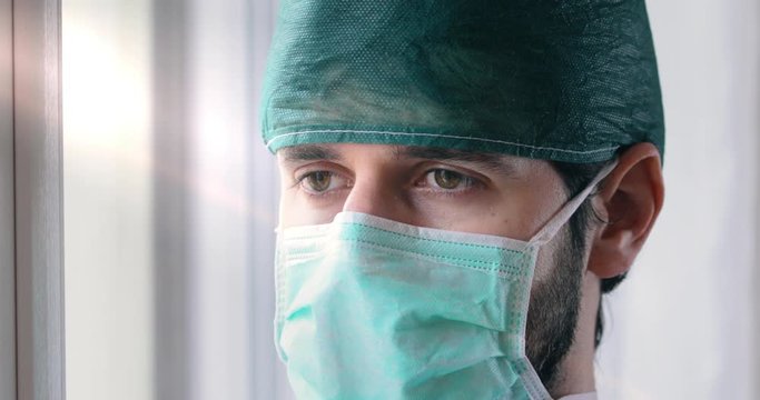 Medico stanco guarda fuori dalla finestra