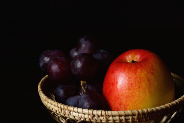 Fototapeta na wymiar Red gala apple and grape in woven bamboo basket.