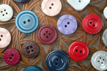 Multicolored buttons on wooden background with arnament