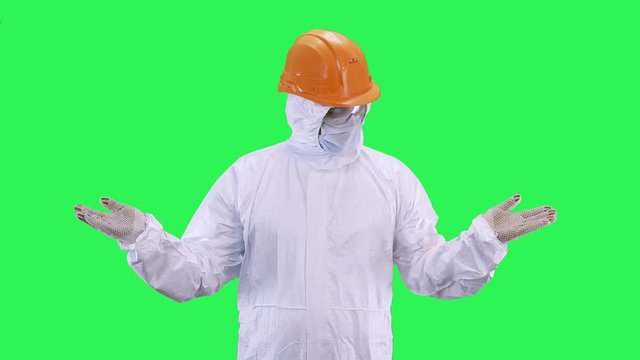 A man in a helmet and a protective suit offers to make a choice, or is it really so.Green screen background.