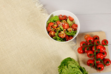 green lettuce with tomatoes, green olives and sunflower seeds in a white bowl with free space for text