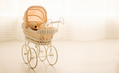 Toy teddy bear sitting in a retro stroller on a white background